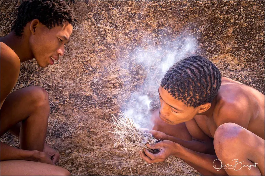 Deux jeunes hommes allument un feu à la main, en Namibie