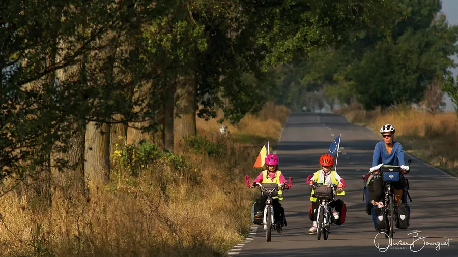 La famille Bourguet à vélo sur une route bordée d’arbres, en Roumanie