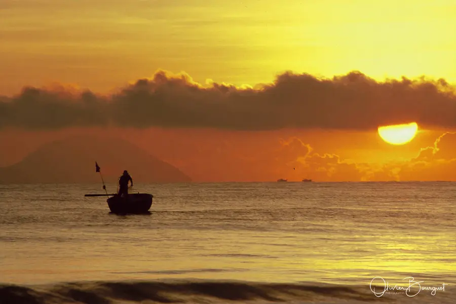 Un pêcheur dans sa barque ronde au soleil couchant, au Vietnam